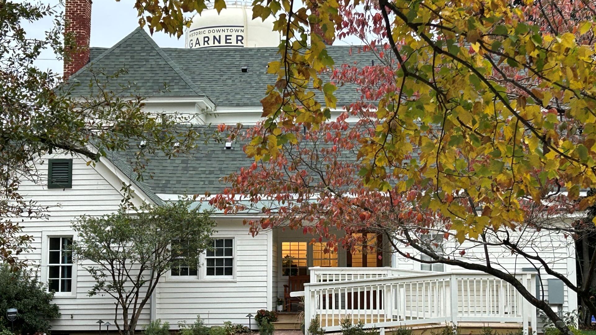 Tree branches with yellow and orange leaves overlaying a white house.