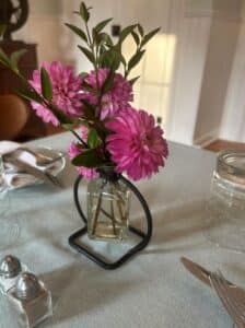 Pink flowers on table with place setting around it.