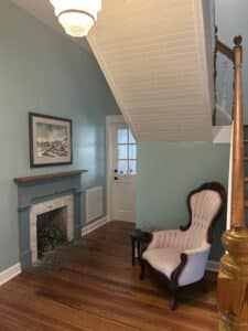 Fireplace across from pink chair under stairwell
