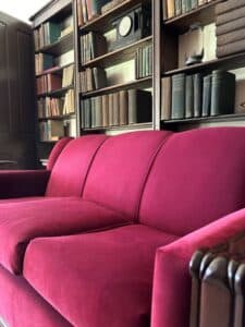 Red couch with books on bookshelf behind it.