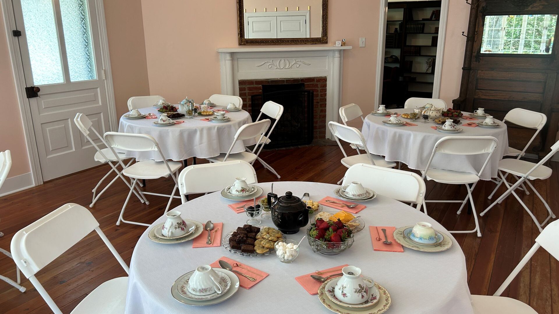 Pink room with white round tables with tea settings.