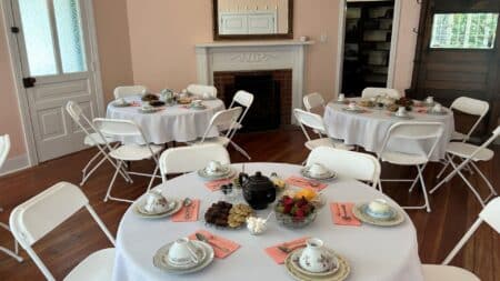 Pink room with white round tables with tea settings.