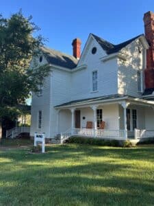 White house with Banks Bed and Breakfast sign on front green grass. 