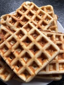 Waffles piled on a plate.
